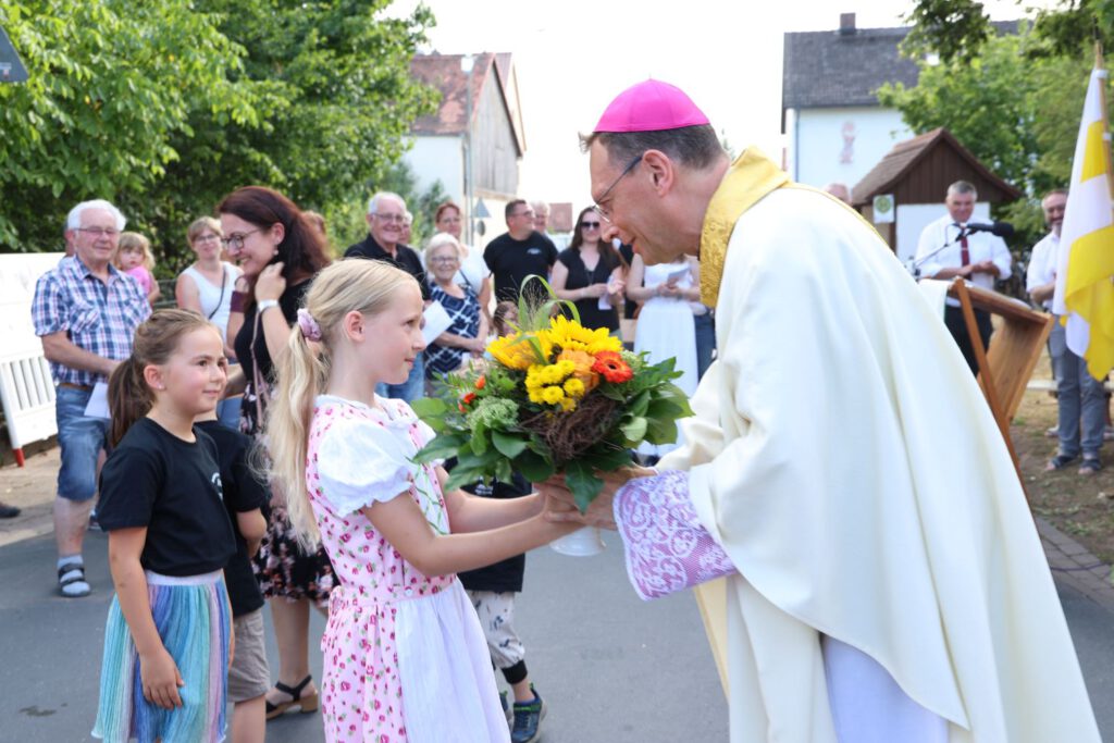 Haider Kinder begrüßen den Erzbischof mit einem Blumenstrauß