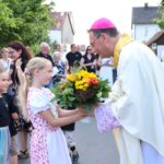 Haider Kinder begrüßen den Erzbischof mit einem Blumenstrauß