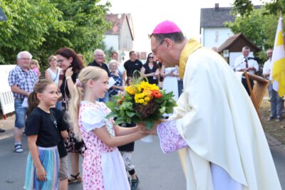 Haider Kinder begrüßen den Erzbischof mit einem Blumenstrauß