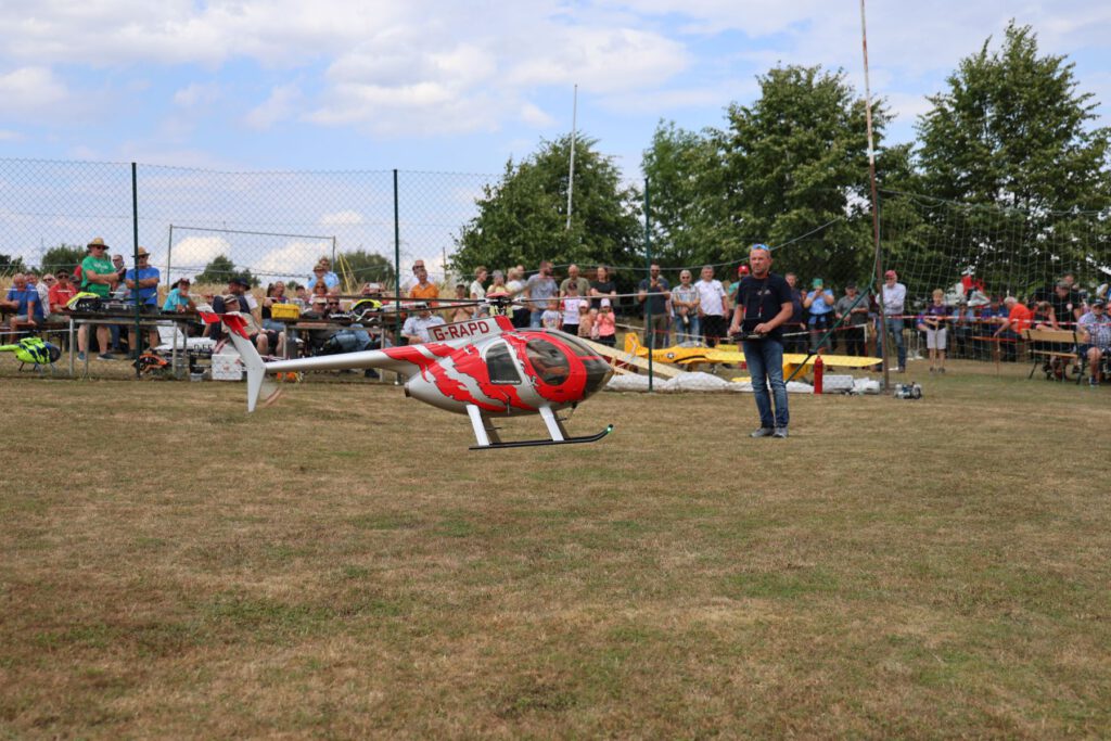 Ein Helikopter fliegt vor den vielen Zuschauern auf dem Flugfeld