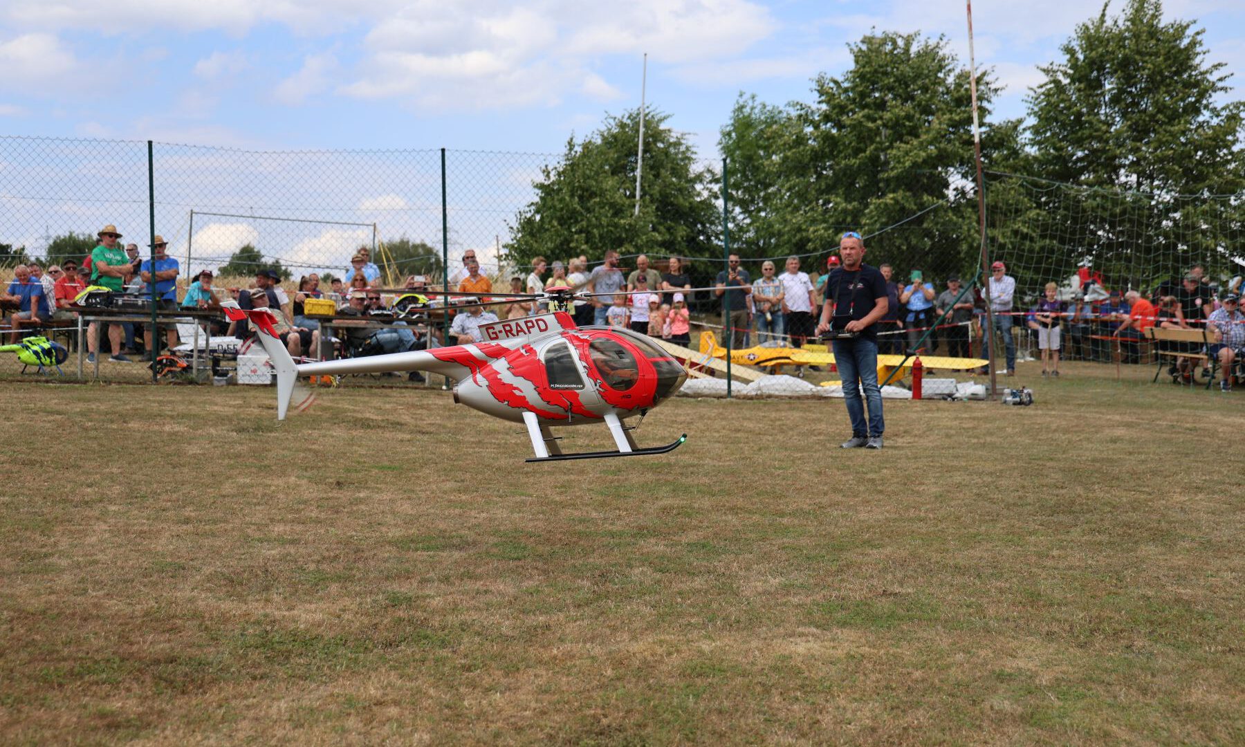 Ein Helikopter fliegt vor den vielen Zuschauern auf dem Flugfeld