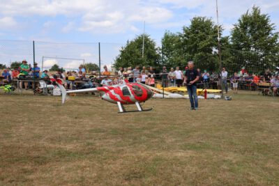 Ein Helikopter fliegt vor den vielen Zuschauern auf dem Flugfeld